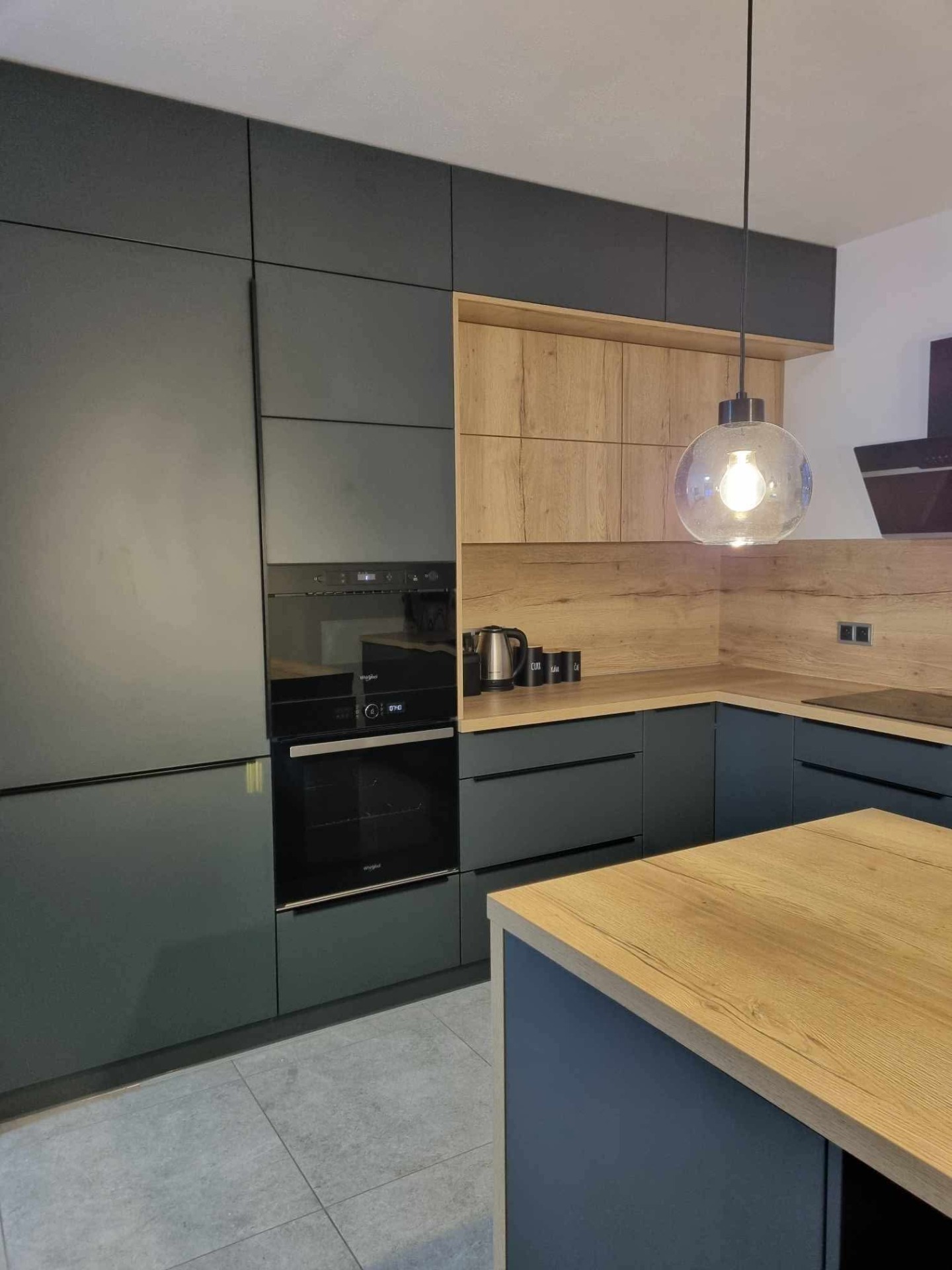 Tato velká moderní kuchyň spojuje eleganci uhlíkově šedé s přirozenou strukturou dubu Halifax. Tmavý, sofistikovaný odstín dodává prostoru hloubku a luxusní vzhled, zatímco přírodní dekor dřeva přináší teplo a útulnost. Výsledkem je vyvážený interiér, který působí moderně, nadčasově a zároveň velmi příjemně pro každodenní život.